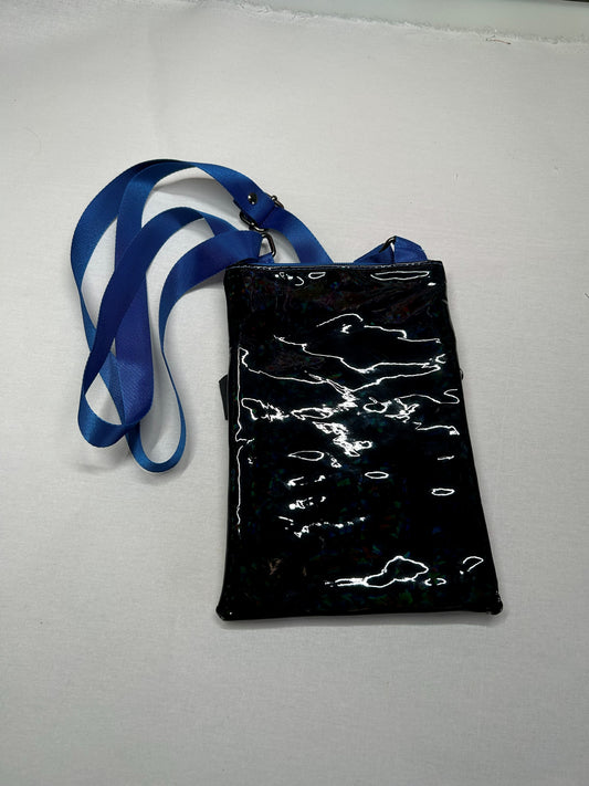 A black, shiny, and reflective object with a blue strap attached to it, placed on a white surface.