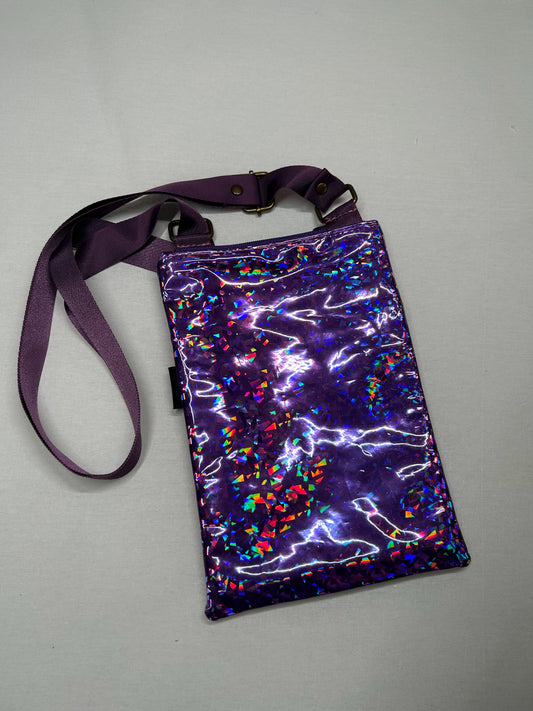 A purple, shiny, and glittery handbag with a purple strap is shown against a plain background.
