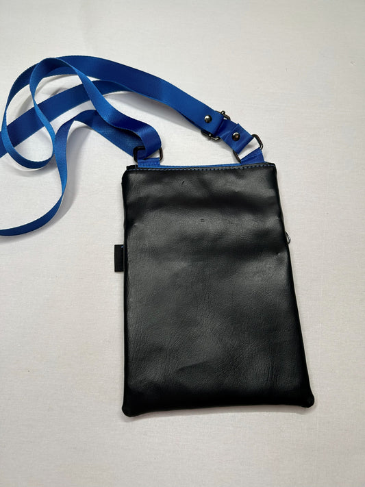 A black leather crossbody bag with a blue strap is shown on a white surface.