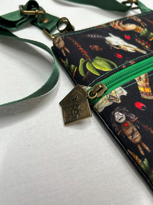 a colorful purse with a green strap and a zipper, featuring a pattern of various objects and characters.