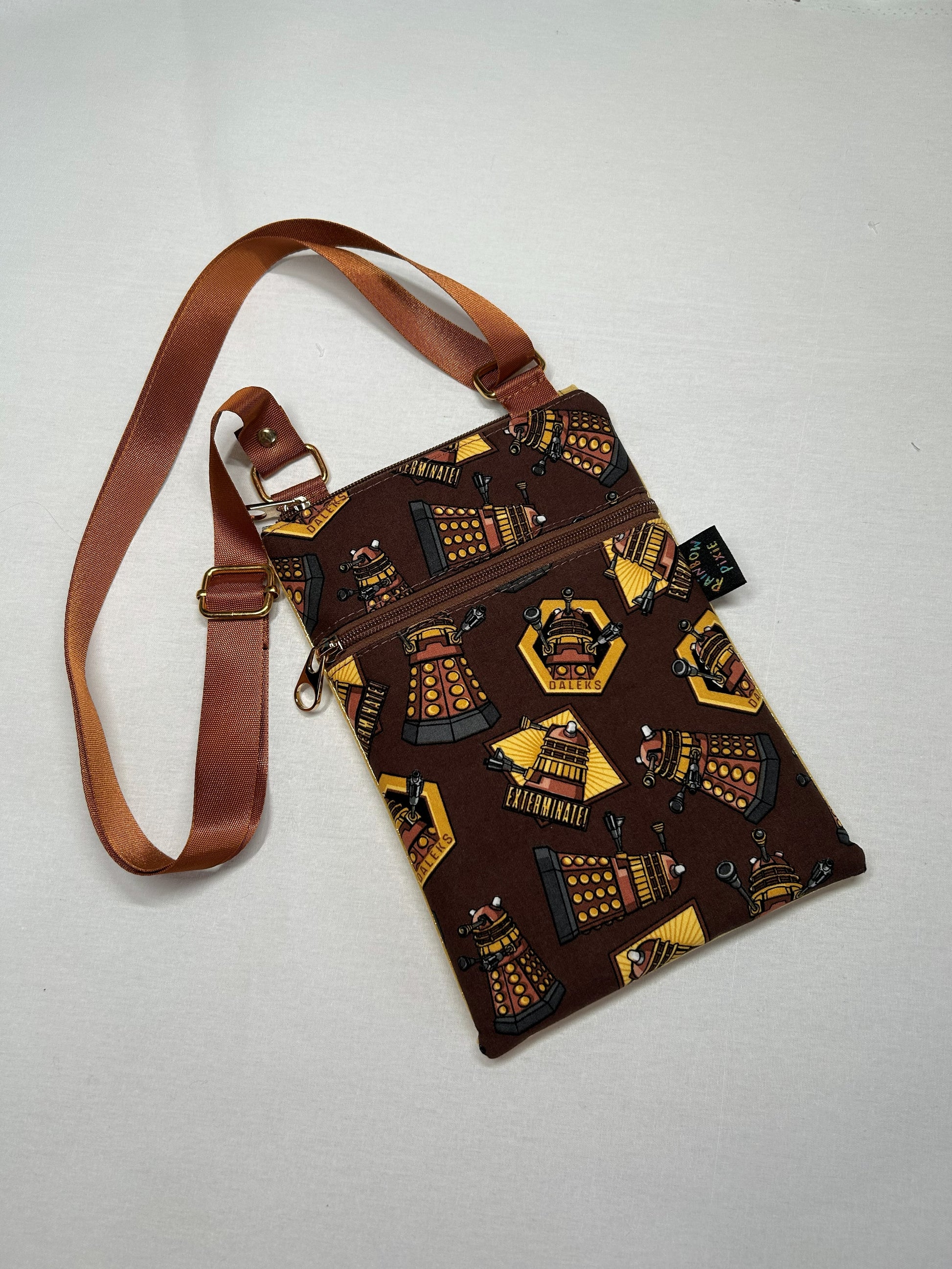 A brown crossbody bag with a pattern of Dalek robots printed on it.