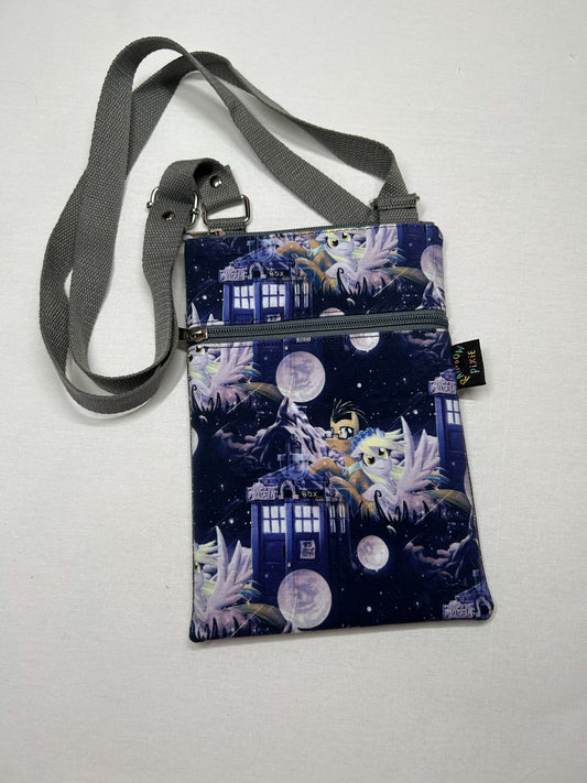A handbag with a unique design featuring a blue and purple space-themed pattern, including images of a blue spaceship, a purple castle, and a purple moon.