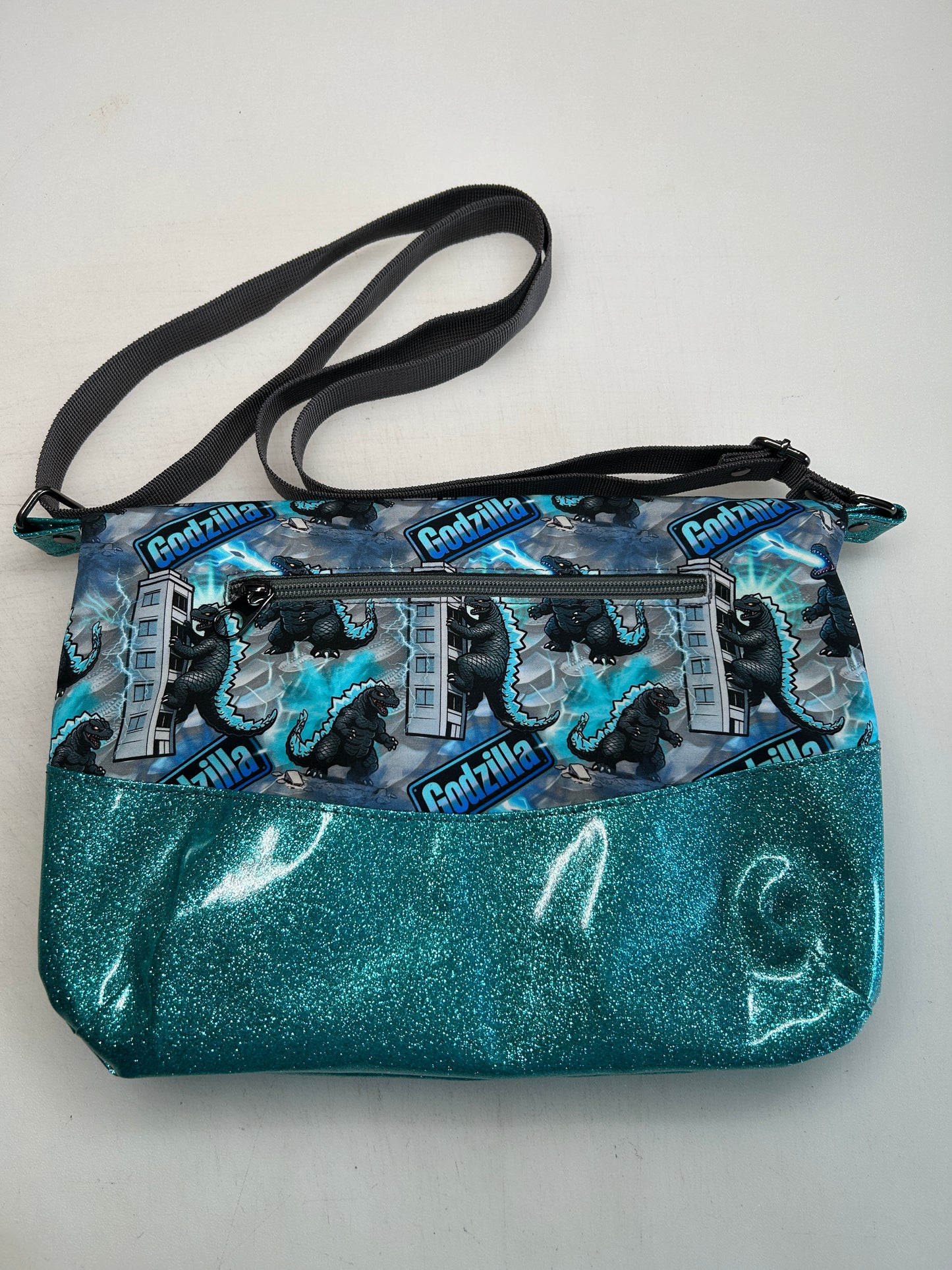 Godzilla Themed foldover crossbody bag with blue glitter bottom
