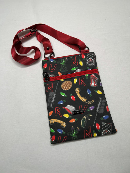 A colorful purse with a pattern of various objects and symbols, including a phone, light bulb, and other icons, printed on it.