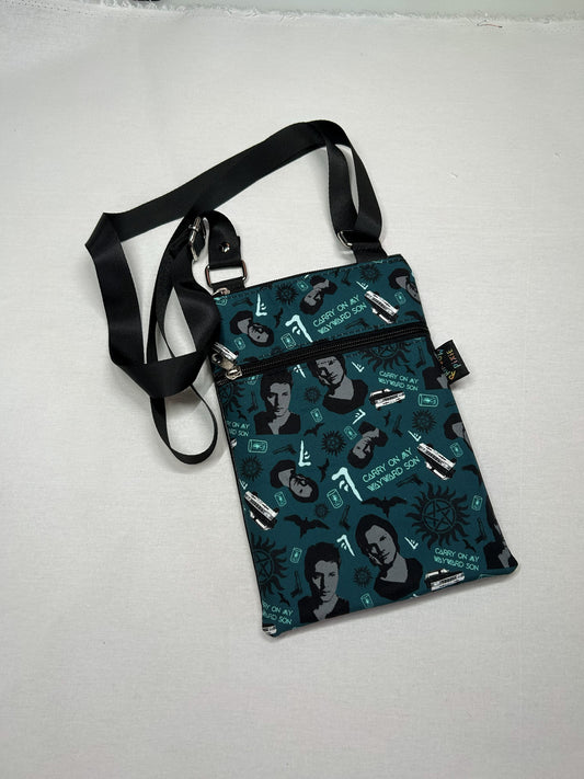 A black and green patterned purse with a black strap and zipper.